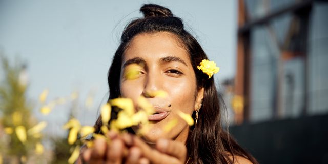 Portrait of young woman blowing kiss of flowers