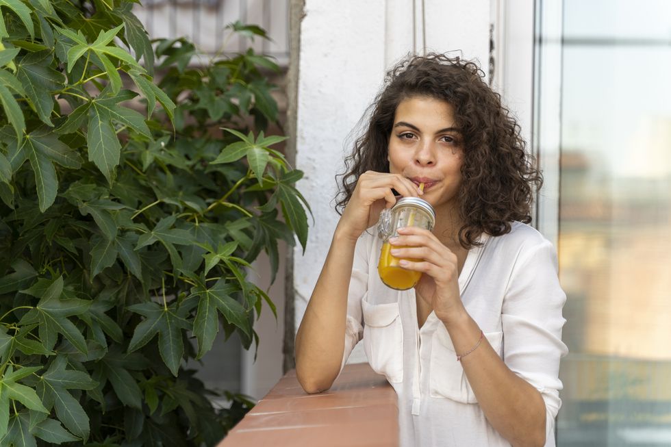 portrait of young woman drinking glass of orange juice