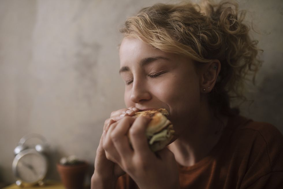 portrait of young woman eating hamburger