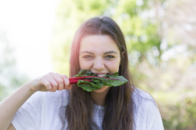 portrait of young woman eating leaf vegetable