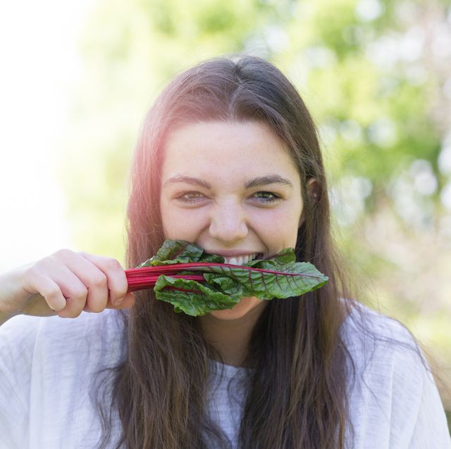 portrait of young woman eating leaf vegetable