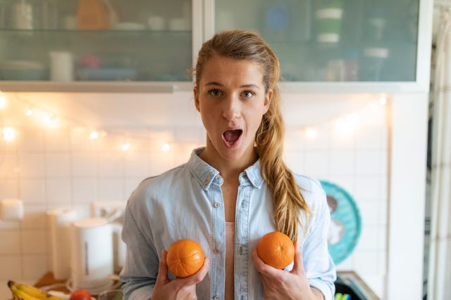 portrait of young woman holding oranges at home