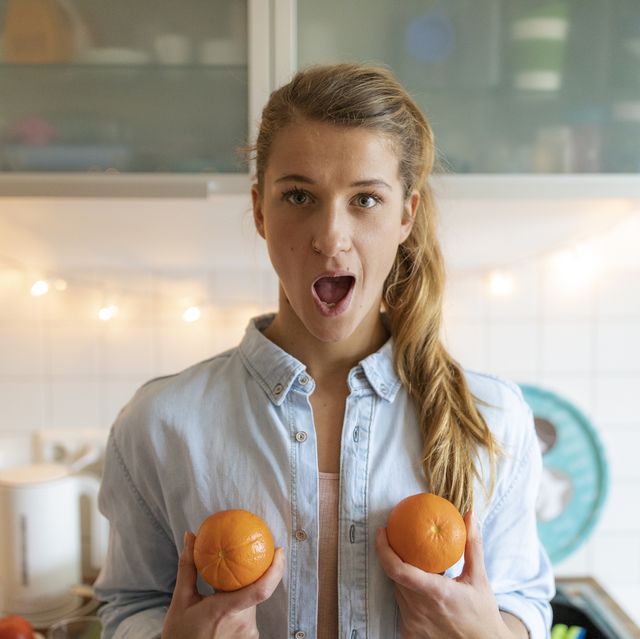 portrait of young woman holding oranges at home