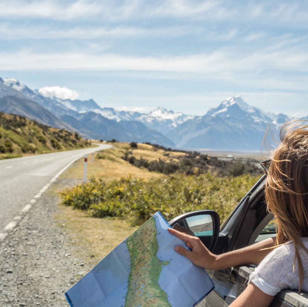 portrait of young woman in car looking at map
