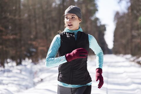 portrait of young woman jogging in winter forest, running recovery
