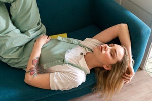 portrait of young woman lying on couch with closed eyes