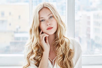 portrait of young woman with blonde hair touching face