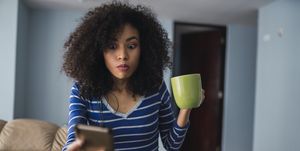 portrait of young woman with mug starring at cell phone