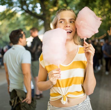 Portrait of young woman with pink candy floss on streetfood festival