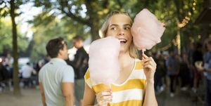 Portrait of young woman with pink candy floss on streetfood festival