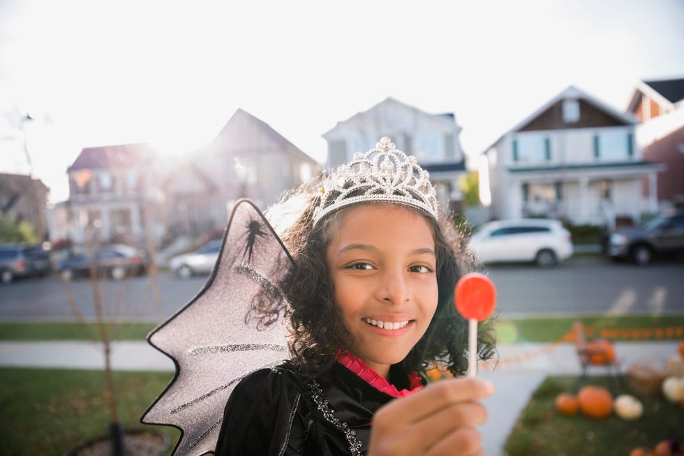 Portrait smiling girl Halloween princess costume enjoying lollipop