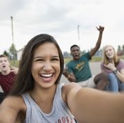 Portrait smiling teenage girl with friends taking selfie on outdoor basketball court