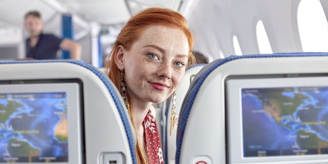 Portrait smiling young woman with red hair and freckles on airplane