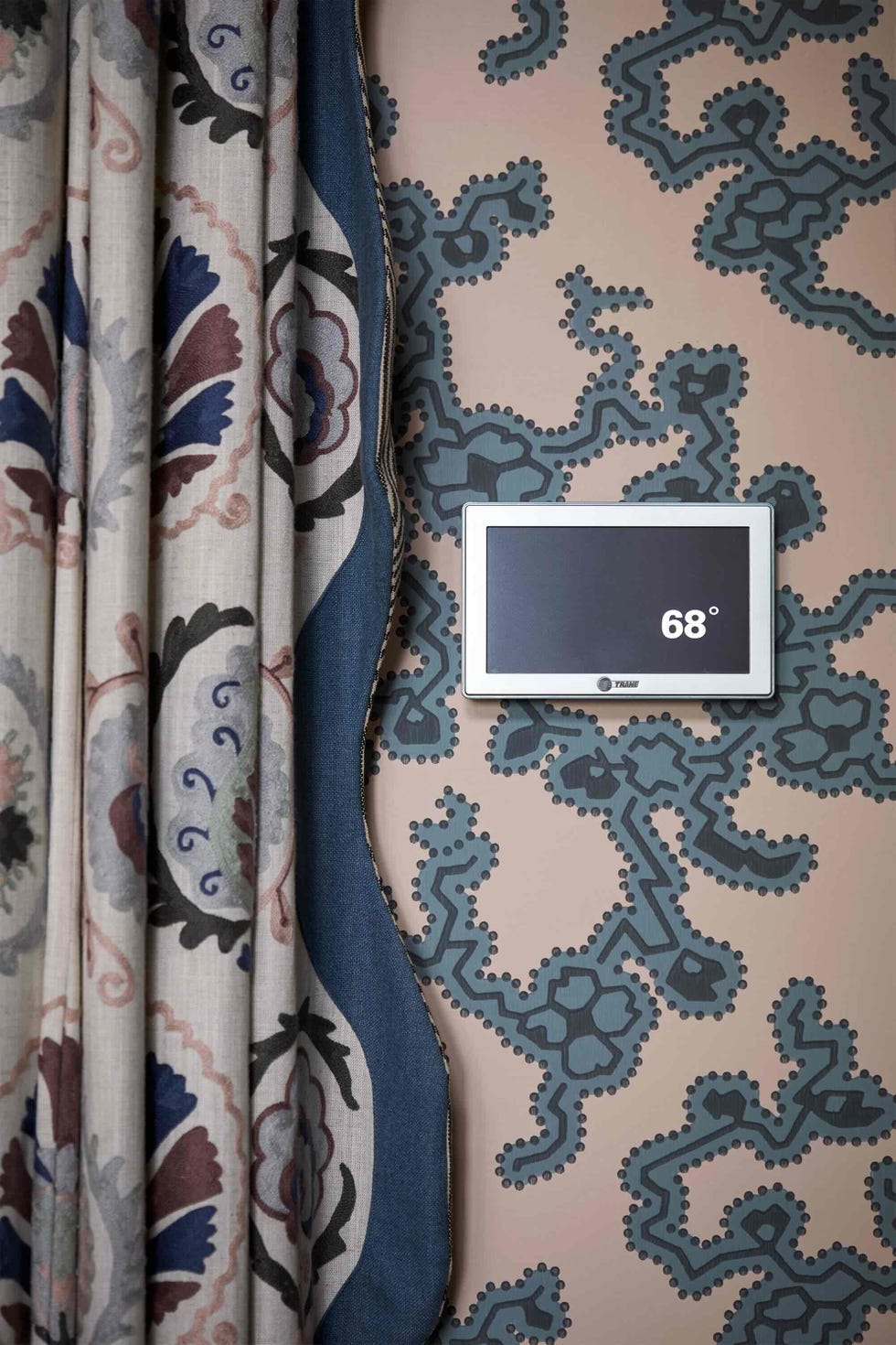 wall with a thermostat display and patterned curtains