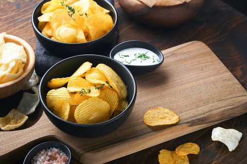 potato corrugatedchips fast food crispy potato chips ceramic black bowl with sour cream sauce and onions in wooden stand on old kitchen table wooden background american tradition hot bbq top view