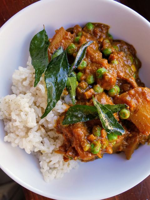 potato curry served with white rice and fried dark green curry leaves