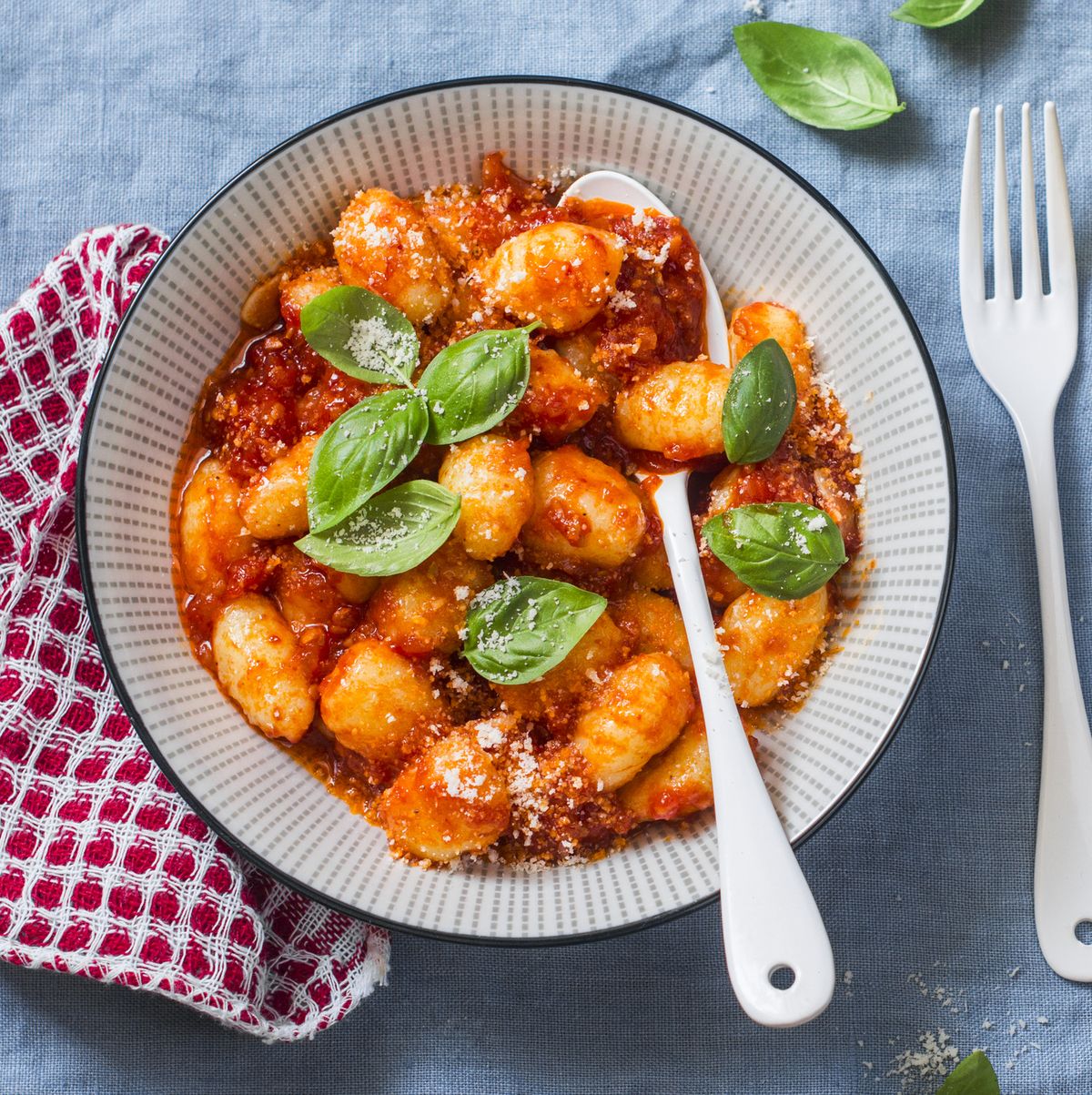 Potato gnocchi with tomato sauce, basil and parmesan on a blue background, top view. Traditional italian food pasta
