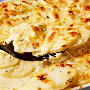 scalloped potatoes in creamy sauce in a white casserole dish baked and topped with cheese