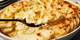 scalloped potatoes in creamy sauce in a white casserole dish baked and topped with cheese