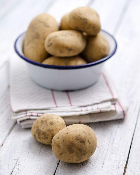 bowl of raw potatoes on folded kitchen towel and wood