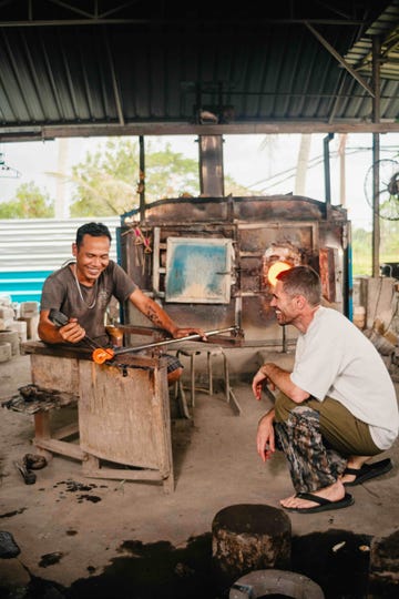 two men crouching and blowing glass
