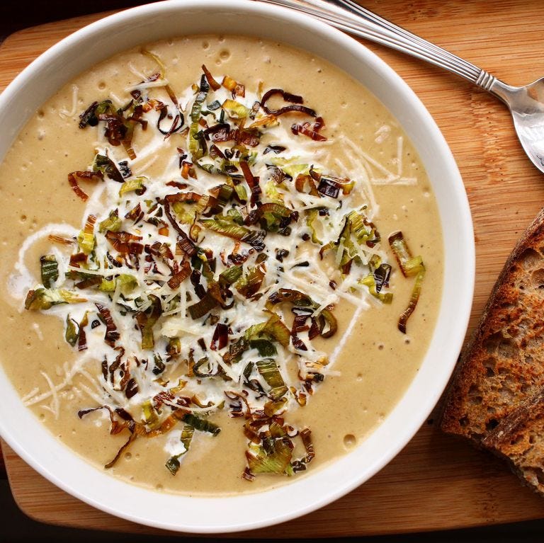 A bowl of potato leek soup garnished with fried leeks and cheese