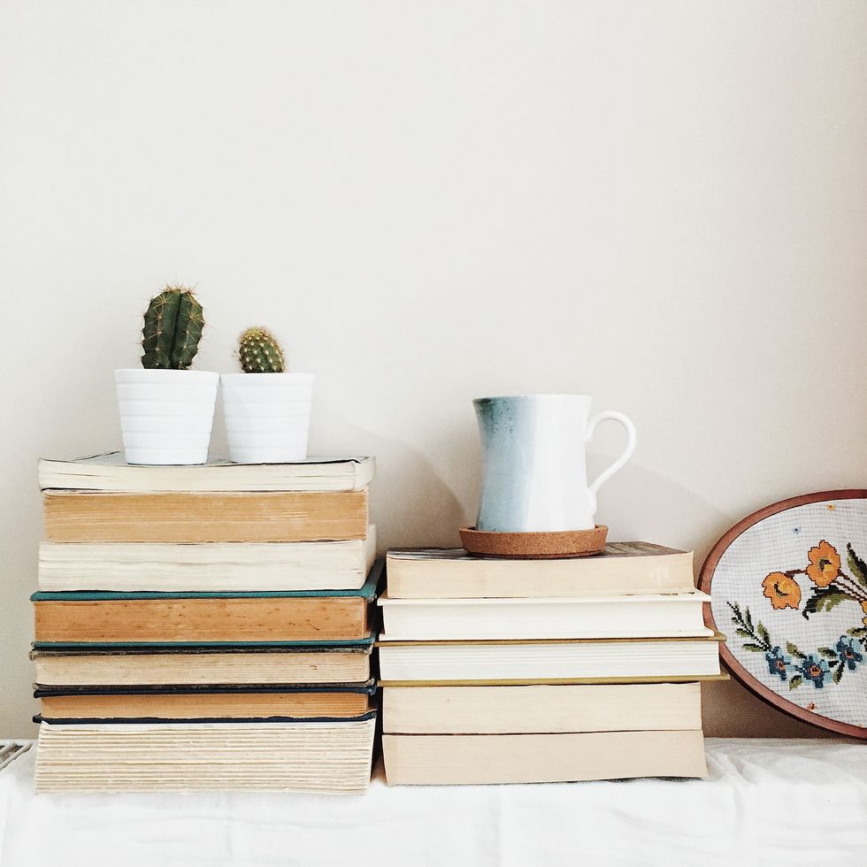 Potted Plant And Jug On Stack Of Books Against Wall
