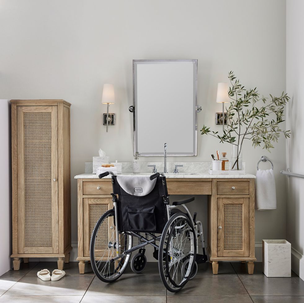 woman in wheelchair in front of black bathroom vanity with marble countertop and tilted vanity mirror