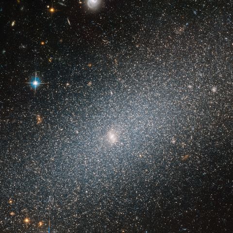 as beautiful as the surrounding space may be, the sparkling galaxy in the foreground of this image from the nasaesa hubble space telescope undeniably steals the show this spotlight hogging galaxy, seen set against a backdrop of more distant galaxies of all shapes and sizes, is known as pgc 29388 although it dominates in this image, this galaxy is a small player on the cosmic stage, and is known as a dwarf elliptical galaxy as the “dwarf” moniker suggests, the galaxy is on the smaller side, and boasts a “mere” 100 million to a few billion stars — a very small number indeed when compared to the milky way's population of around 250 to 400 billion stellar residents
