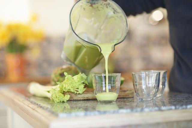 Pouring a fresh smoothie drink in kitchen.