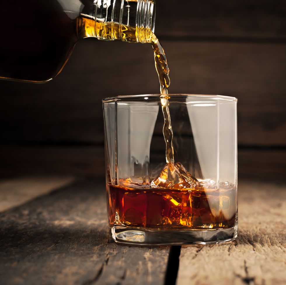 pouring glass of whiskey, close up whisky on the rocks