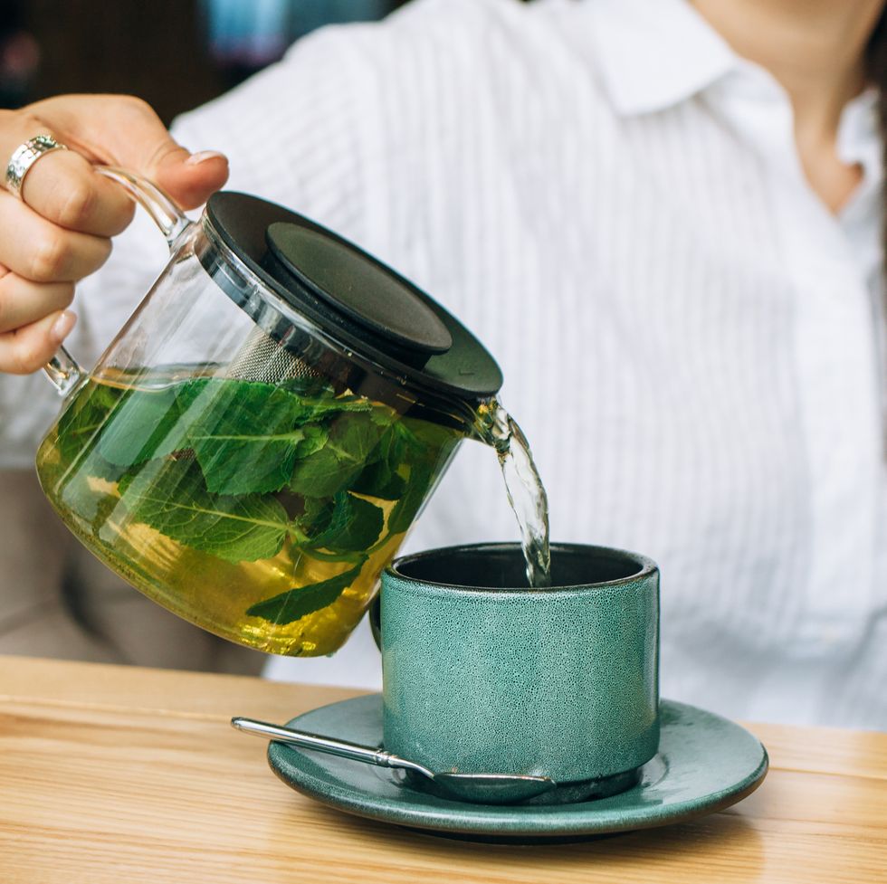 pouring green tea with mint from a glass teapot