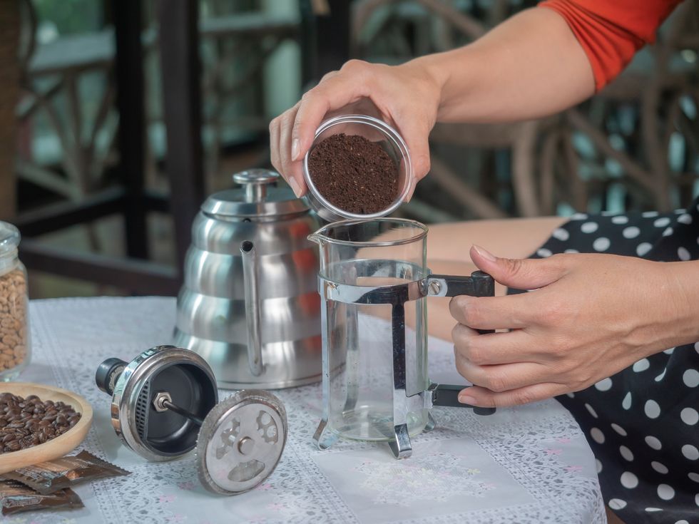pouring ground coffee into french press cup