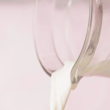 pouring milk into glass, pink background