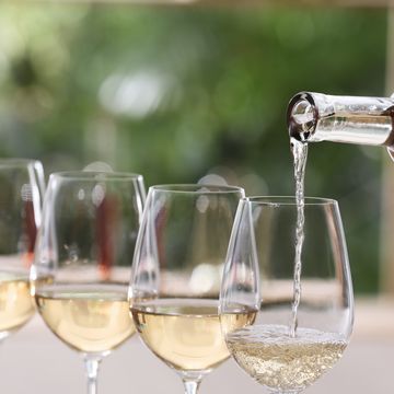 pouring white wine from bottle into glass on blurred background