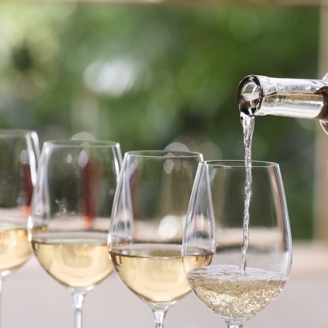 pouring white wine from bottle into glass on blurred background