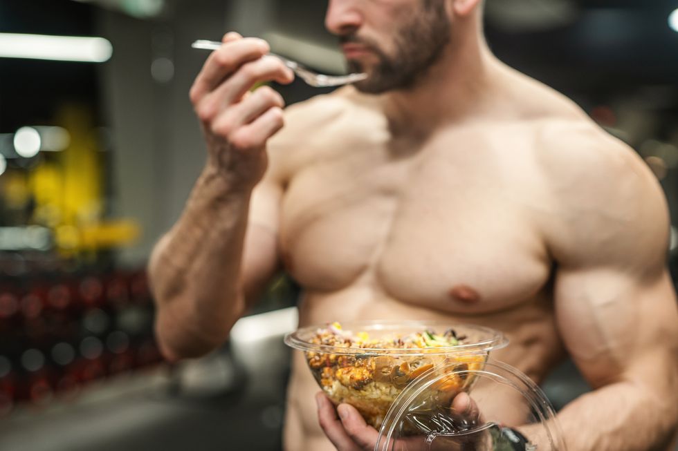 powerful athletic man with great physique eating a healthy salad