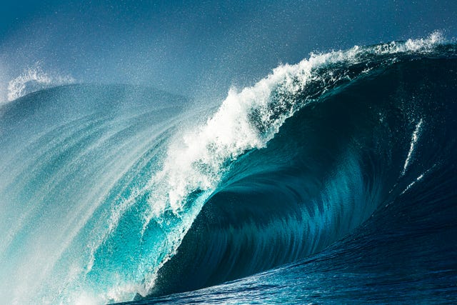 powerful blue and aquamarine wave breaking in the open ocean on a sunny day