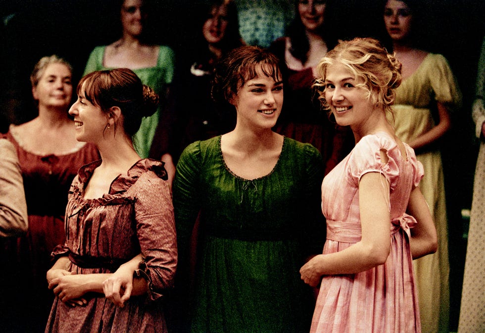 group of women in historical dresses interacting at an event