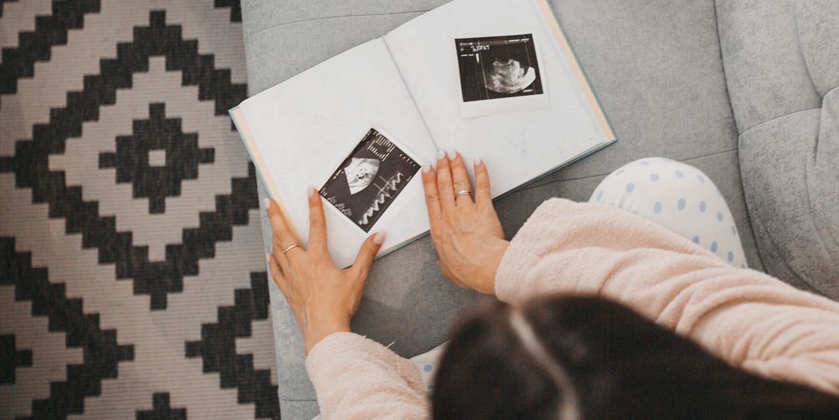 woman adding ultrasound photos to pregnancy journal
