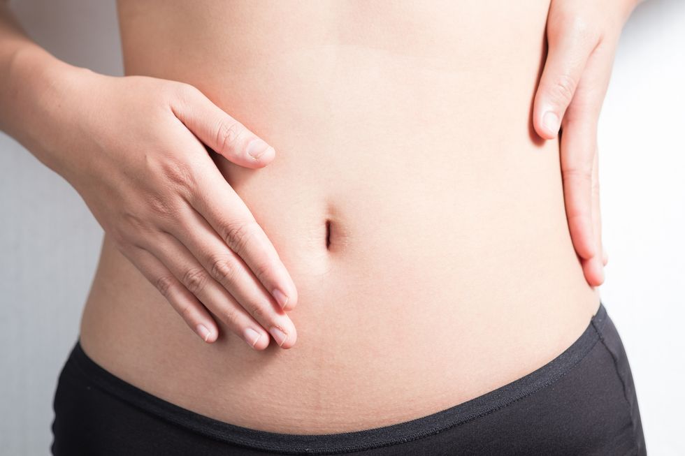 pregnancy or diet concept, female hands protecting the stomach on white background