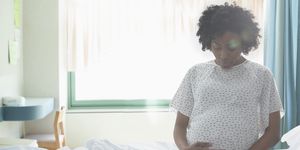 pregnant african american woman holding her stomach in hospital