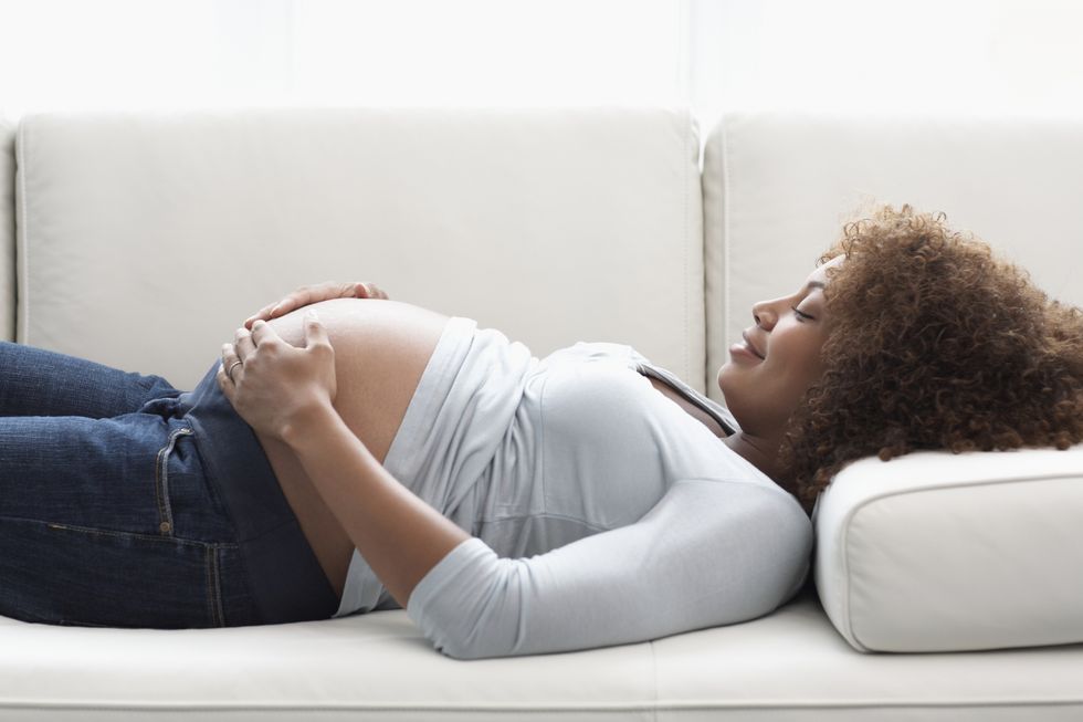 pregnant woman holding stomach on sofa