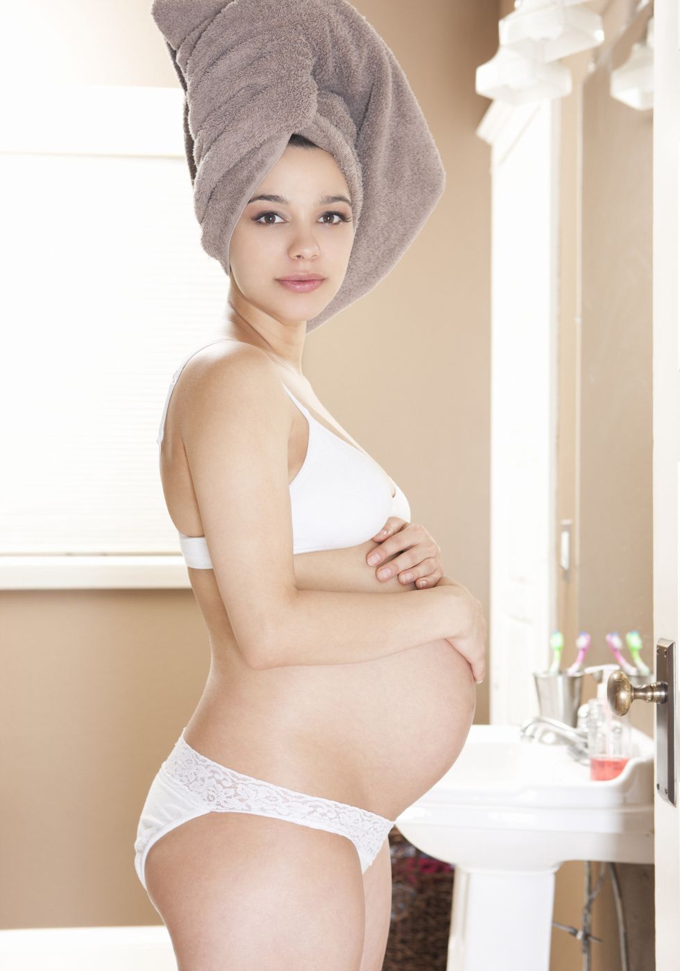 una chica embarazada, con una toalla en la cabeza, en el baño de su casa