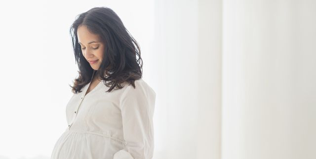pregnant hispanic woman touching her belly