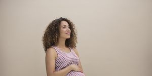 a pregnant mixed race lady holds bump thoughtfully