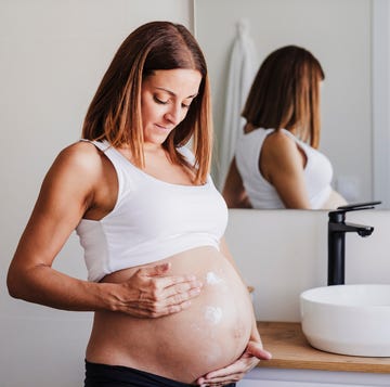 mujer embarazada echandose crema en la tripa