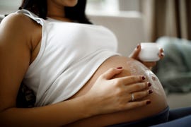 mujer embarazada echándose crema en la tripa