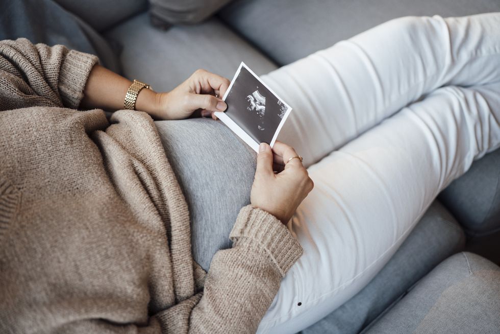 pregnant woman holding ultrasound photo at home
