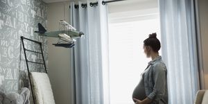 Pregnant woman looking out nursery window